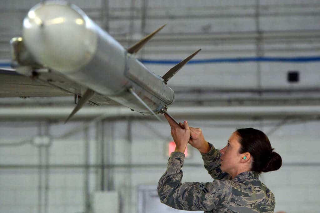 Militar da Força Aérea dos EUA ajustando um míssil AIM-120C AMRAAM na asa de um F-16