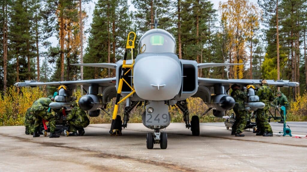 Militares carregando armamentos em um caça Saab JAS-39 Gripen