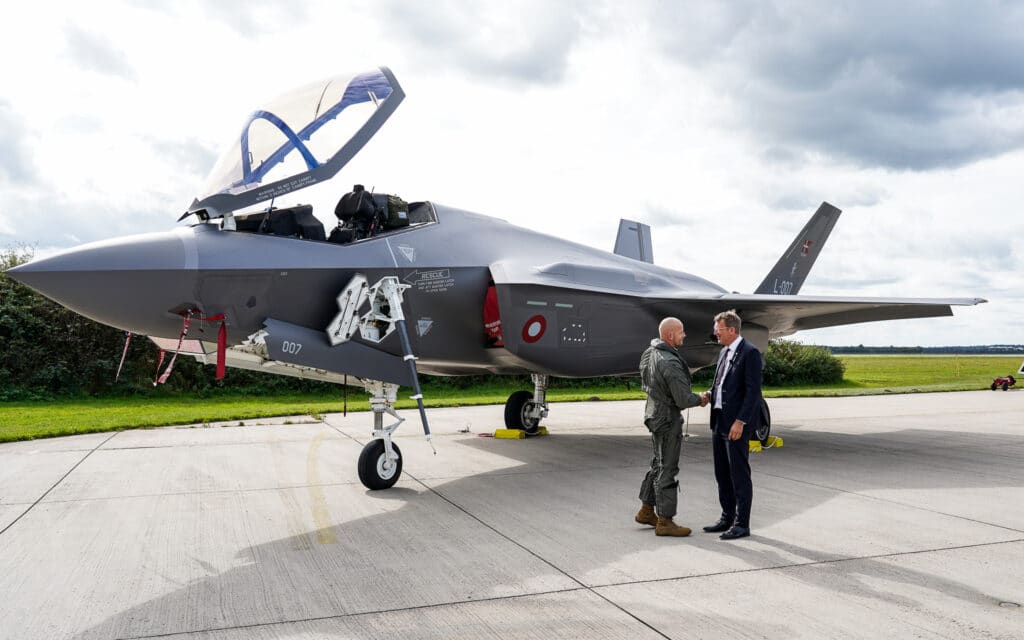 Imagem mostra dois homens em frente a um dos quatro primeiros F-35 a chegarem na Dinamarca.