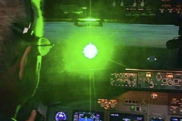 Image shows pilot being illuminated by green laser.